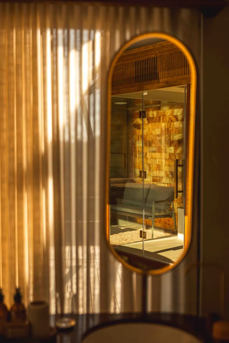 An oval mirror reflecting the suite through linen