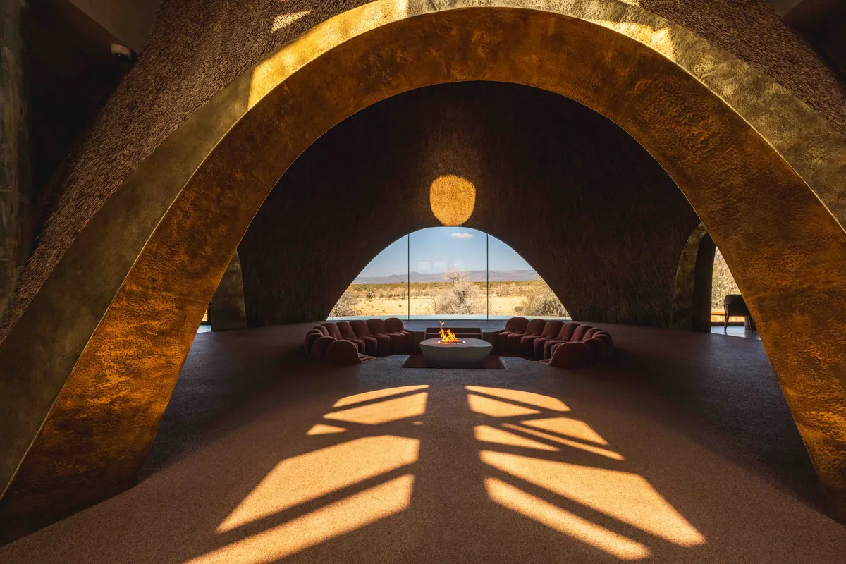 A sculpted thatch archway framing the sunken lounge and the plains