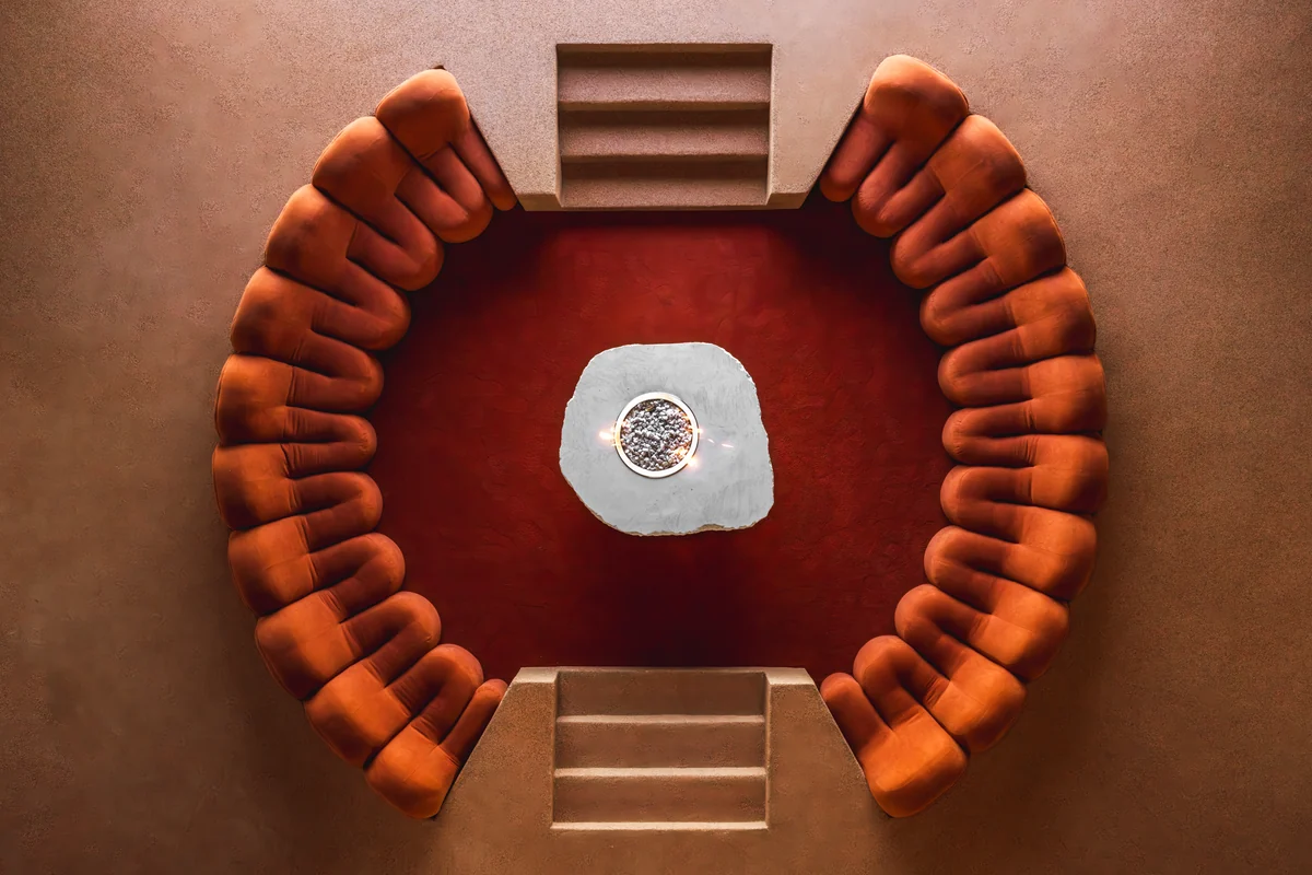 The sunken fire lounge seen from directly above, a ring of velvet around the hearth