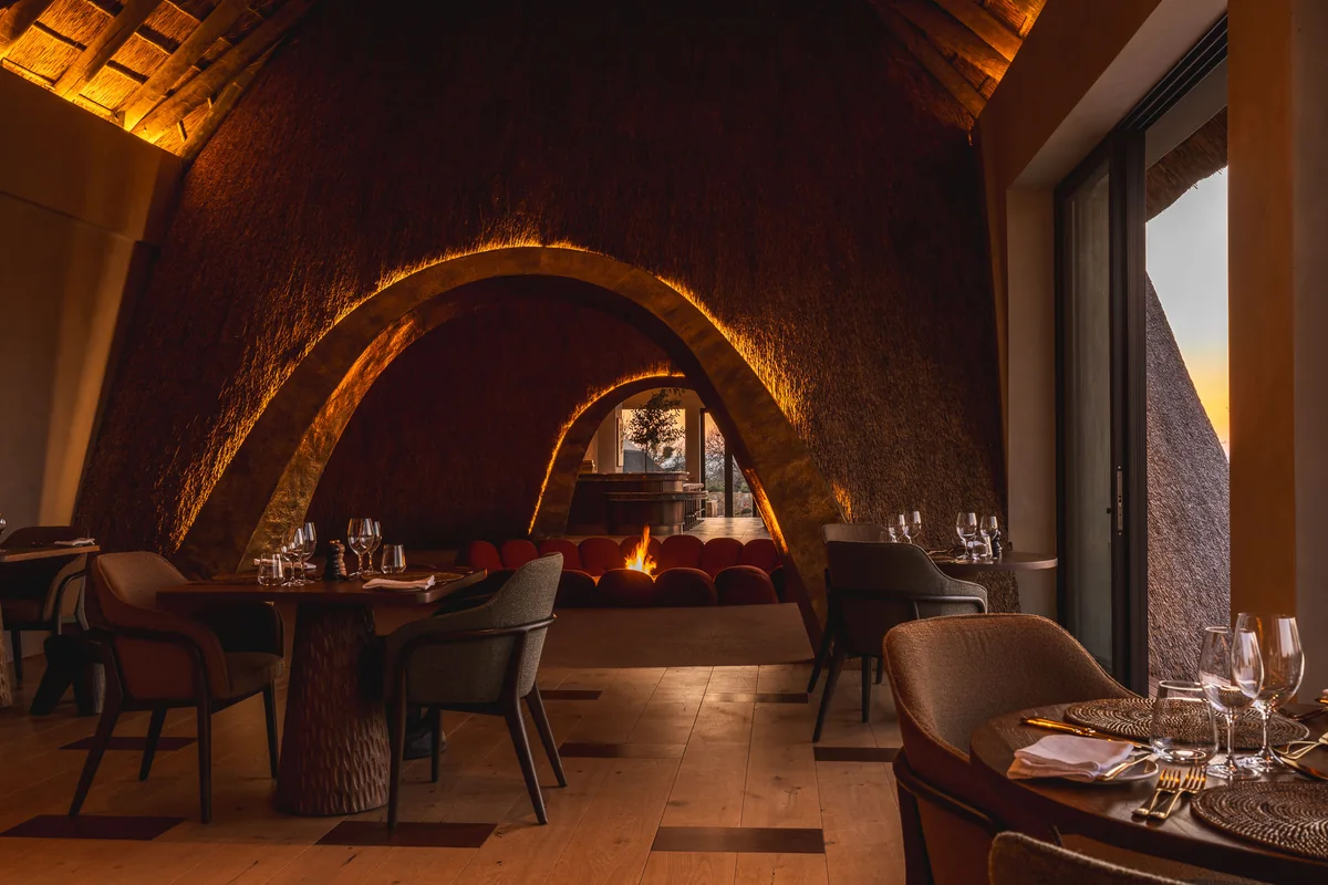 Dining beneath an arch of thatch, tables set for evening