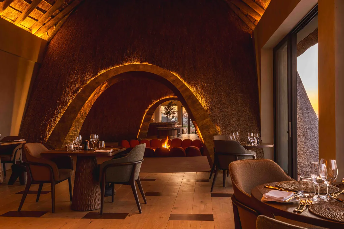 Dining room beneath arched thatch, tables set for evening