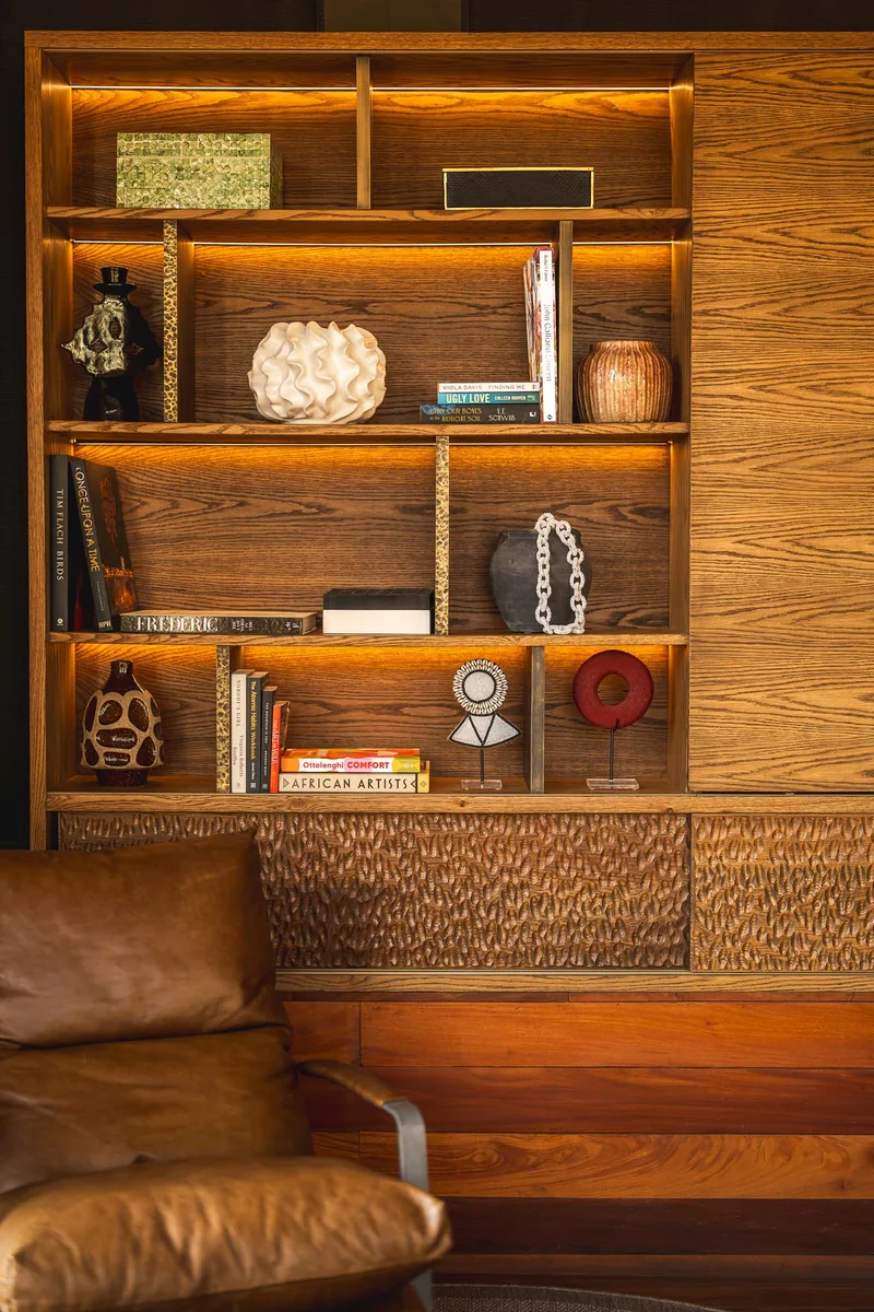 Lit timber shelves above a leather chair